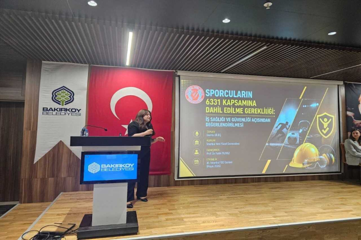 Bir konferans salonunda, Bakırköy Belediyesi Flaması ve Türk bayrağı önündeki kürsüde sunum yapan bir kadın ve arkasındaki büyük ekranda "Sporcuların 6331 Kapsamına Dahil Edilme Gerekliliği" başlıklı sunum slaytı yer alıyor.