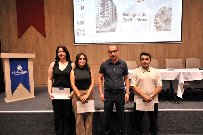 Bir seminersalonunda, arkalarında 'Dinlediğiniz İçin Teşekkür Ederim' yazılı projeksiyon perdesi önünde yan yana durarak sertifikalarıyla poz veren üç katılımcı ve bir yetkili.