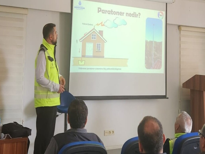 Bir eğitmen, "Paratoner nedir?" başlıklı slaytın önünde katılımcılara yıldırımdan korunma sistemlerini anlatıyor.