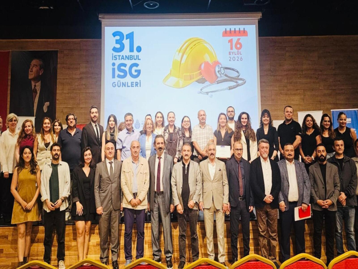 Fotoğrafta, 31. İSG Günleri kapsamında bir sahnede iki sıra halinde yan yana durarak toplu anı fotoğrafı çektiren kalabalık bir katılımcı grubu yer almaktadır.